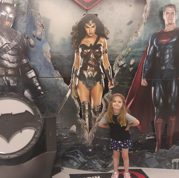 My granddaughter with movie poster in her super hero pose